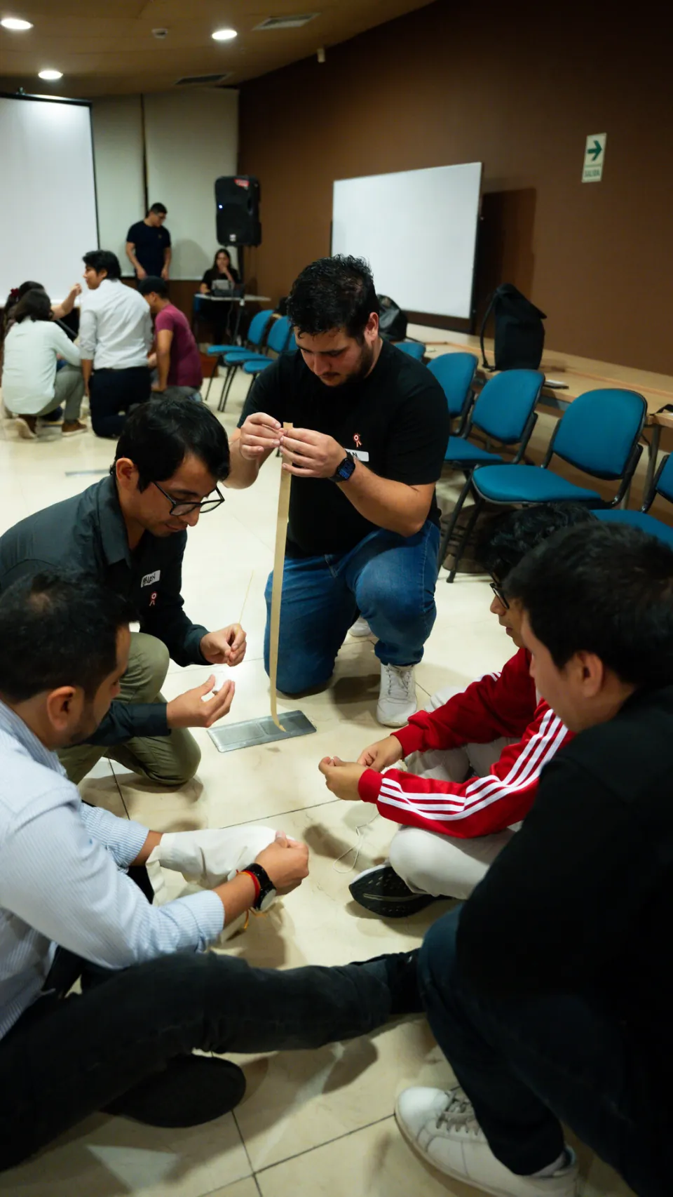 Equipo de participantes trabajando en el suelo con materiales durante un reto colaborativo del taller Ágil de Verdad Edición 01