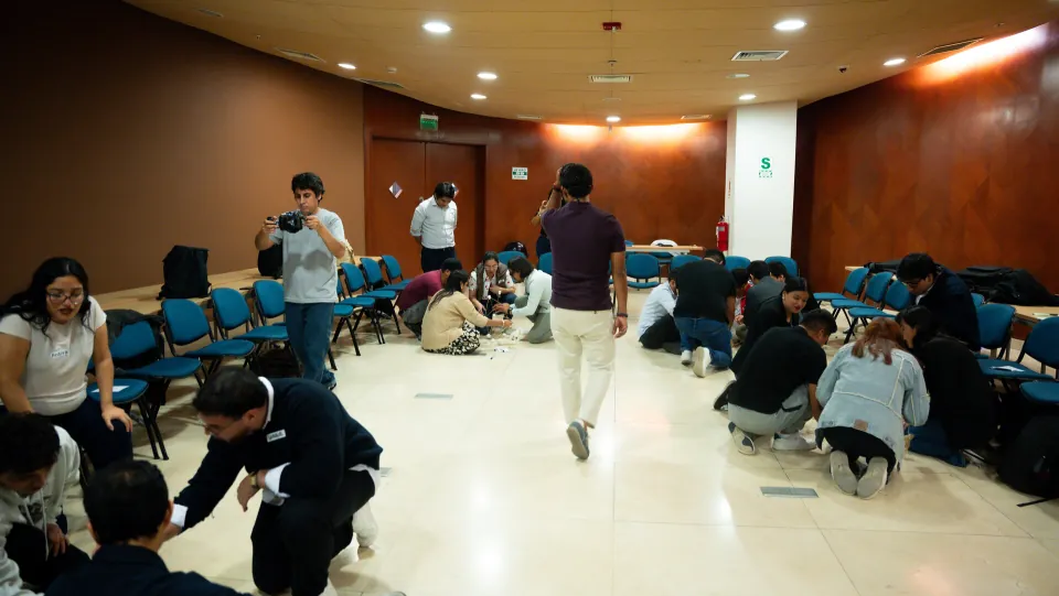 Equipos construyendo a contrarreloj — Ágil de Verdad Ed. 01 Lima Varios equipos de profesionales trabajando en el piso de la sala durante el reto colaborativo de Ágil de Verdad Edición 01 en Miraflores