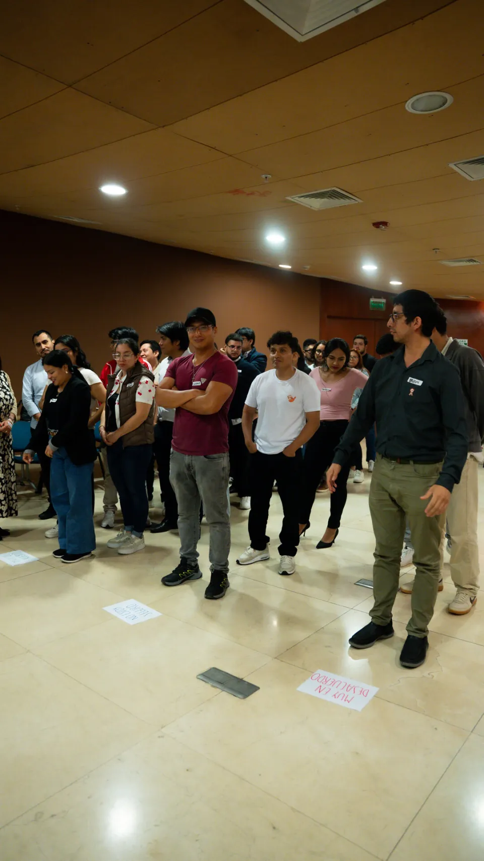 Participantes de pie formando una línea sobre tarjetas en el piso durante una dinámica de decisión en Ágil de Verdad Edición 01